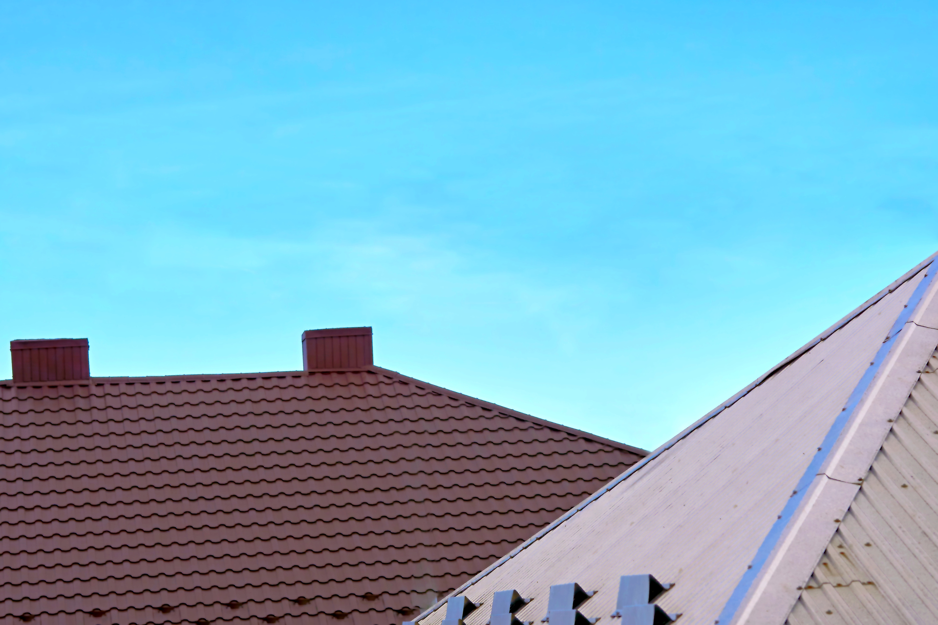 Plastic metal tile profile on the roof of a house and blue clear sky